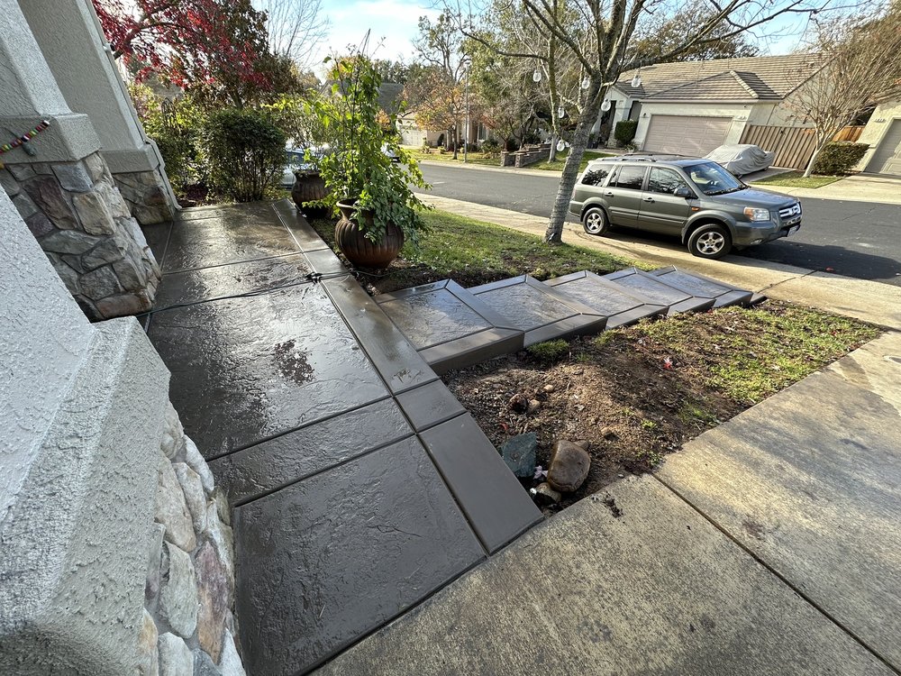Freshly poured concrete walkway with decorative scoring leading from front entry to driveway in residential setting