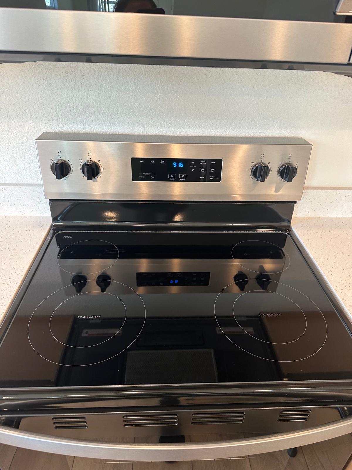 Spotless stainless steel stove with gleaming glass cooktop after professional deep cleaning service