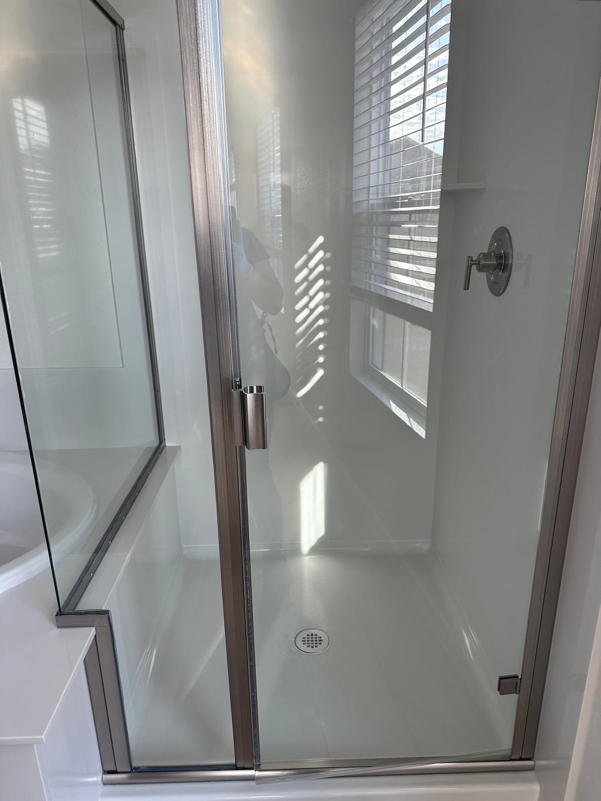 Spotless white bathroom shower with glass door and gleaming fixtures after professional deep cleaning service