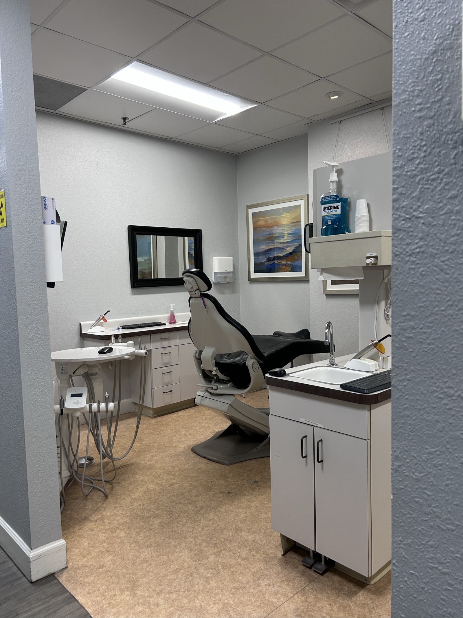 Clean dental examination room with white cabinets, dental chair, and sanitized surfaces in Elk Grove